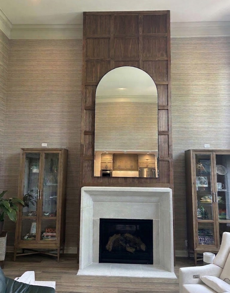 Two-story wood fireplace surround with an arched mirror